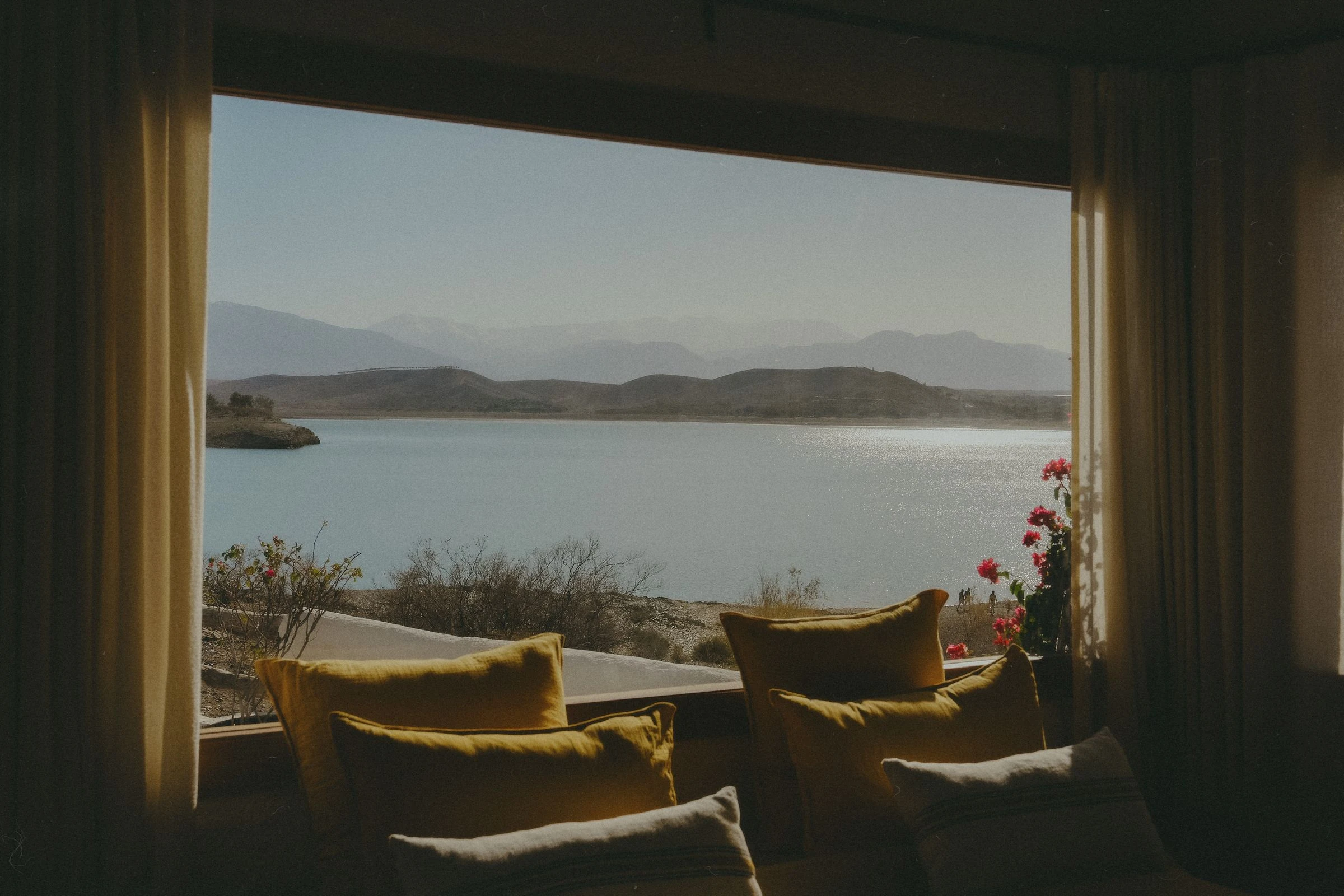 Großes Fenster mit Blick auf einen See und Berge, vom Innenraum aus gesehen