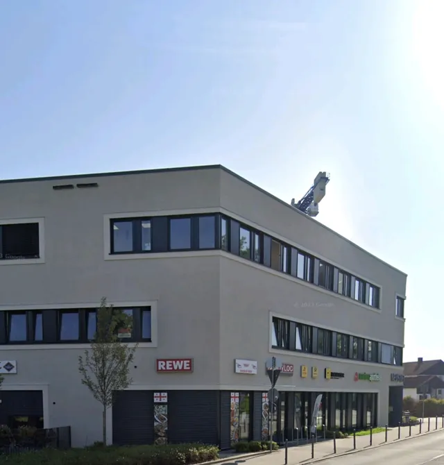 Graues Gewerbegebäude in Passau mit durchgehenden Fensterbändern und Ladenflächen im Erdgeschoss
