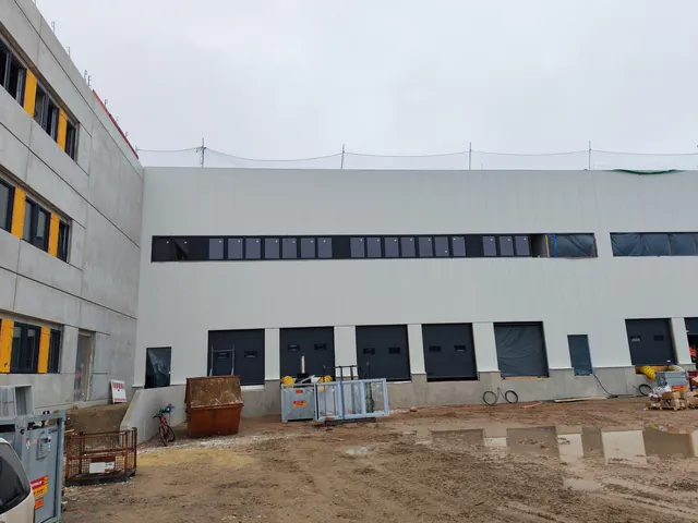 Weiße Halle am Innstolz-Gebäude mit oberem Fensterband und Verglasung im Erdgeschoss