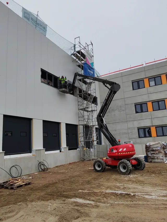 Arbeiten von einer Hubarbeitsbühne am oberen Fensterband des Innstolz-Gebäudes