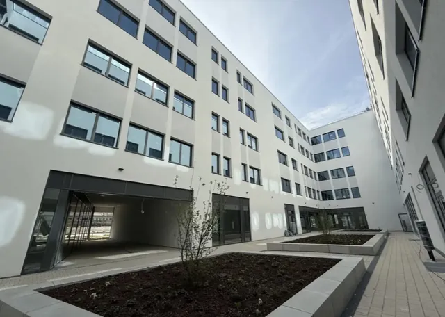 Innenhof des Lillenthallcenters mit unterschiedlich großen Fenstern und bepflanzten Aufenthaltsbereichen