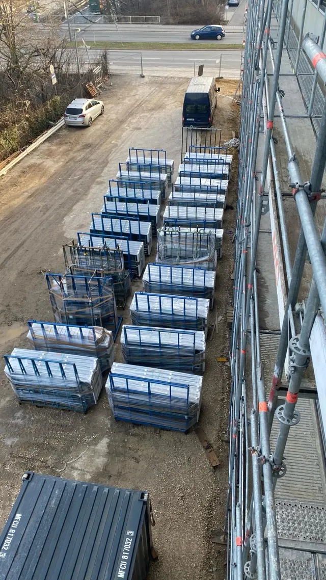 Auf Transportgestellen gelagerte Fensterelemente unterhalb eines Baugerüsts in Regensburg
